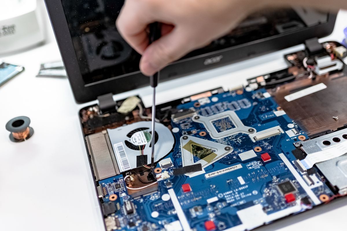 Intervenție la un laptop desfăcut, cu sistemul de răcire vizibil